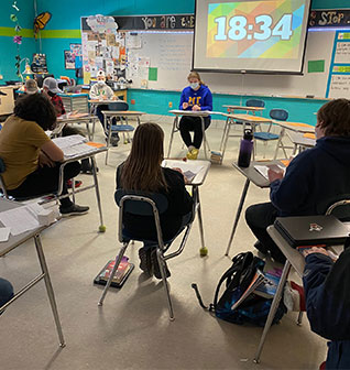 Students sitting in a circle in their desks doing an exam