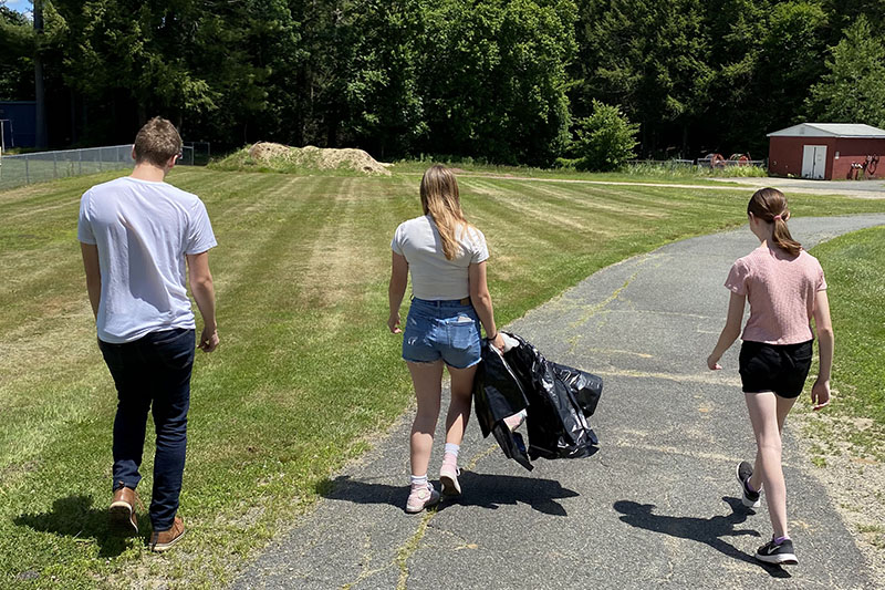 Three students walking along paved path