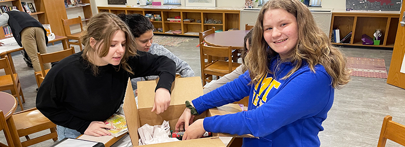 Two happy students packing a box