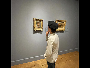 A student studying paintings on the wall of Clark Art Museum