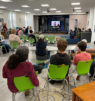 Students in green chairs engaged in watching a student presentation