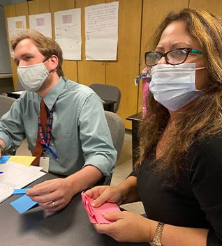 Teachers in meeting holding colorful paper